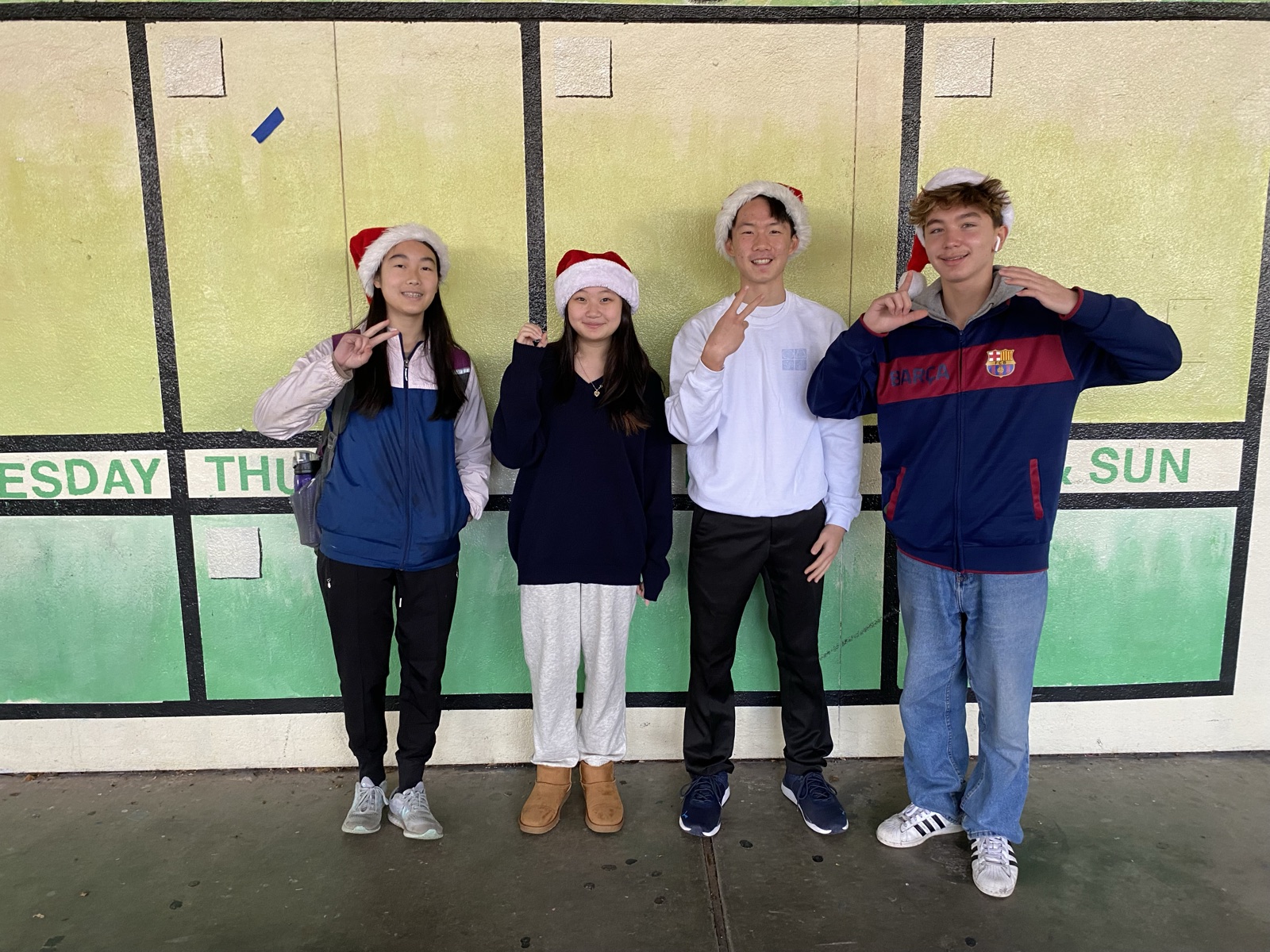 Freshman class officers in Santa hats by the school calendar mural